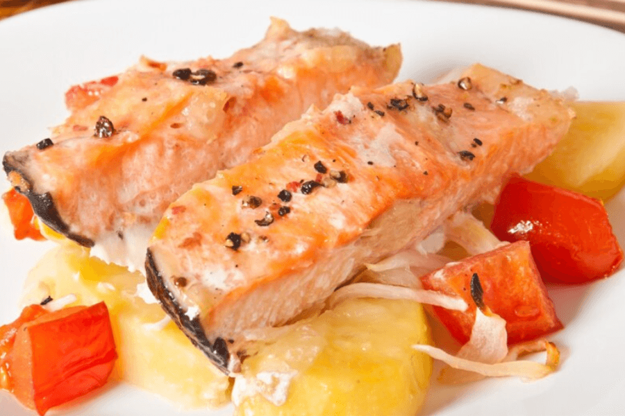 Golden, bite-sized salmon pieces served on a platter with lemon wedges, garnished with fresh dill and accompanied by a dipping sauce.