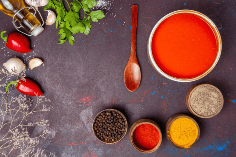 A close-up of a bowl filled with homemade sloppy joe seasoning, showing a blend of spices like paprika, chili powder, garlic powder, and onion powder, placed on a wooden kitchen countertop with measuring spoons.