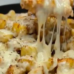 Cheesy Garlic Parmesan Chicken and Potatoes being lifted from a skillet.